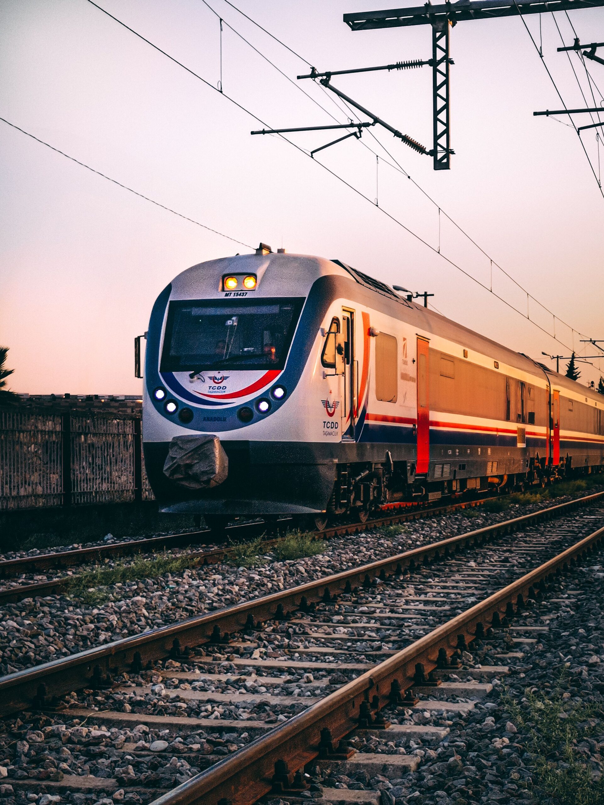 Stylish passenger train traveling on railway tracks during a picturesque sunset.